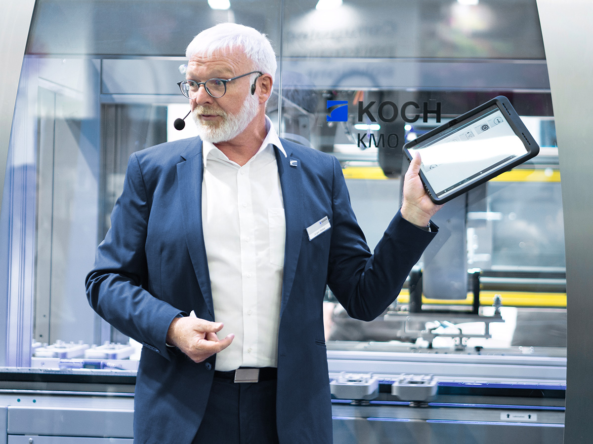 KOCH Mitarbeiter präsentiert die digitale Bedienoberfläche der modularen KMO Verpackungsmaschine auf einem Tablet